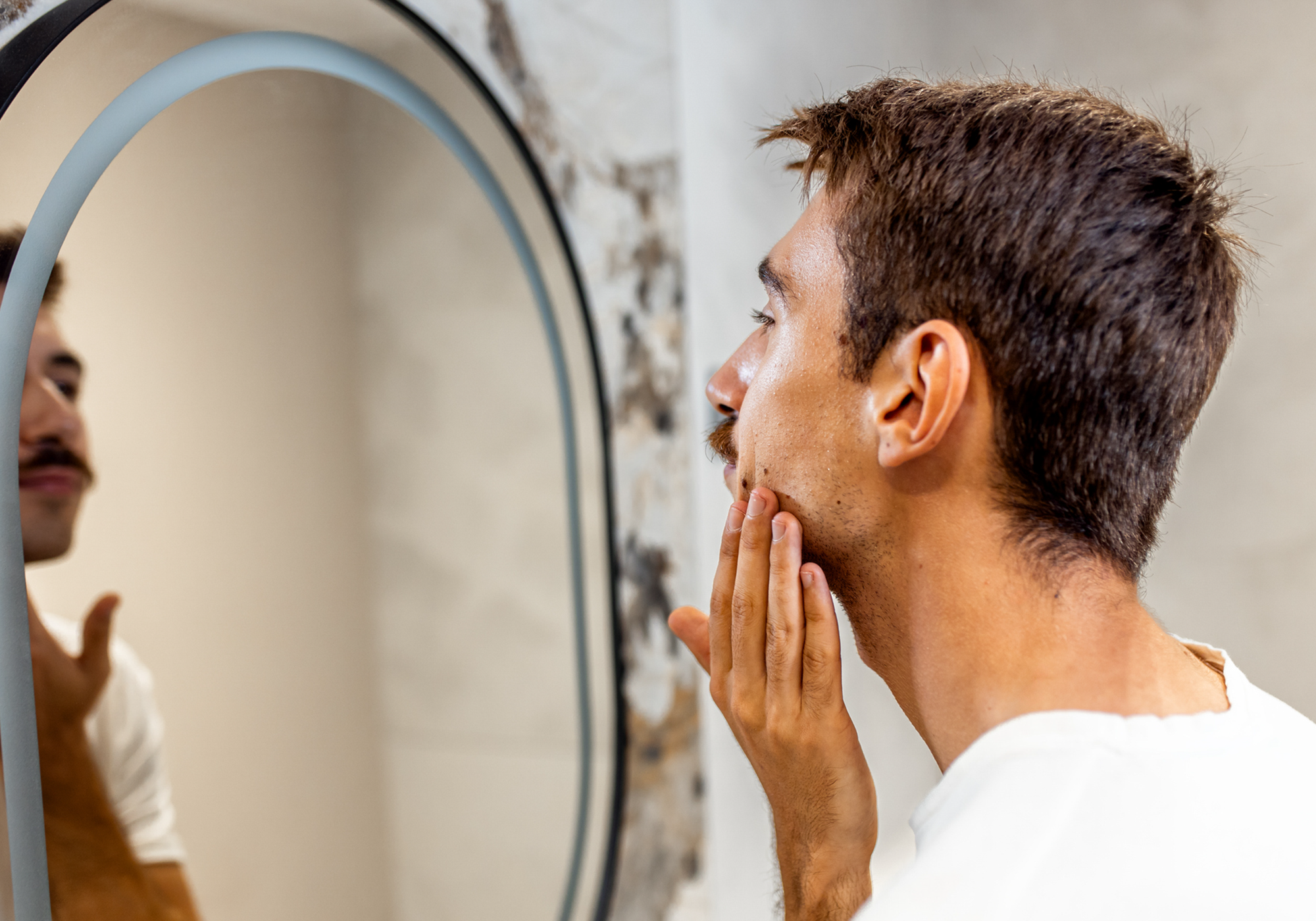 Man looking in mirror applying cream